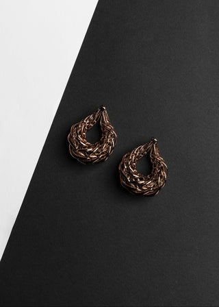 Pair of braided bronze earrings on a black and white background