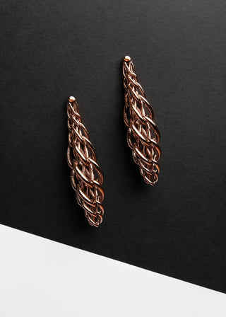 Pair of braided rose gold earrings on a black background