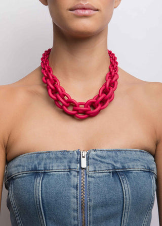 Person wearing a bright red chain necklace with a plain background