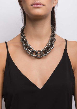 Person wearing a large chain necklace against a plain background