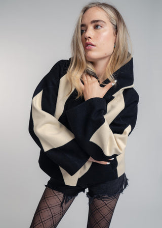 Person wearing a black and beige jacket with a plain background