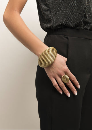 Person wearing a gold bracelet and ring on a plain background