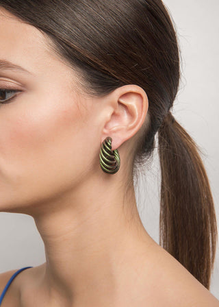 Close-up of a woman wearing a spiral beetle colored earring with a plain background