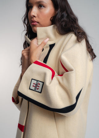 Woman wearing a beige jacket with red and black accents, featuring a visible brand logo.