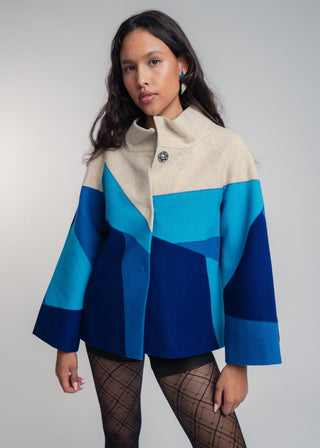 Woman wearing a blue and beige jacket against a plain background