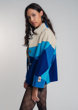 Woman wearing a blue and beige patterned jacket against a plain background
