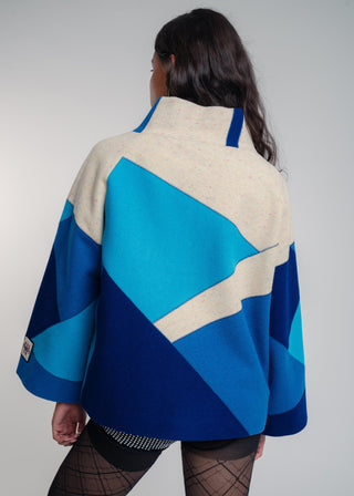 Person wearing a blue and beige patterned jacket against a plain background