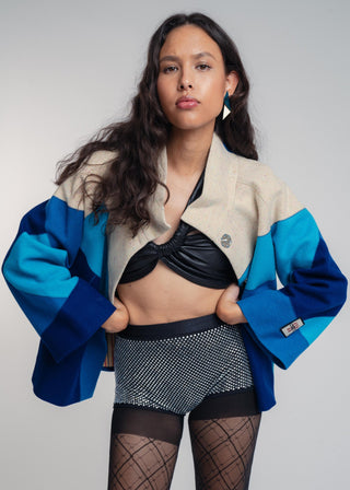Woman wearing a stylish outfit with a blue and beige jacket on a plain background