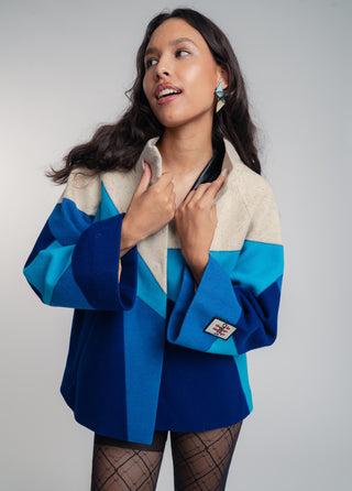 Woman wearing a blue and beige patterned jacket against a gray background