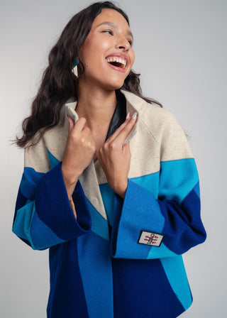 Woman wearing a blue and beige jacket with a visible brand logo on a gray background