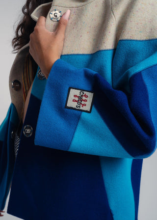 Close-up of a blue and beige jacket with a brand logo on a gray background