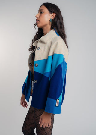 Woman wearing a blue and beige jacket with a white background