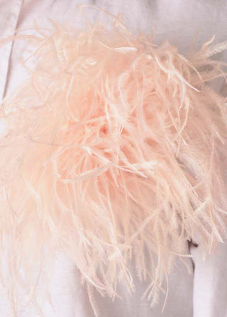 Close-up of a light pink feathered garment on a white background