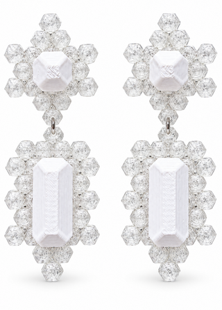 A pair of dramatic drop earrings featuring large white emerald-cut center stones surrounded by halo clusters of clear round and baguette-cut stones, set in a silver-toned metal against a white background.
