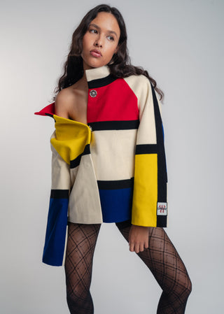 Woman wearing a colorful jacket with a geometric pattern on a plain background
