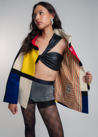 Woman wearing a colorful jacket with a geometric pattern on a plain background