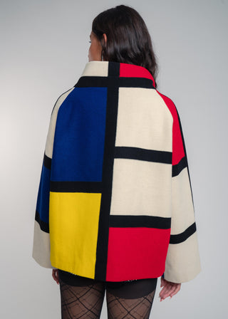 Person wearing a colorful geometric patterned coat against a plain background