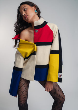 Woman wearing a colorful geometric-patterned coat against a plain background