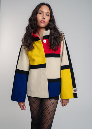 Woman wearing a colorful geometric-patterned coat against a plain background