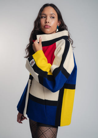 Woman wearing a colorful geometric-patterned coat against a plain background