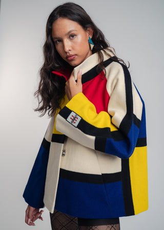 Woman wearing a colorful jacket with geometric pattern on a plain background
