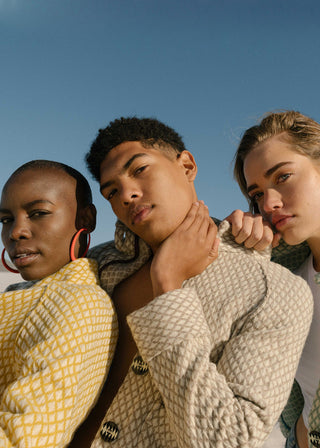 Three people standing close together wearing the Short Jacket V3 against a clear blue sky.