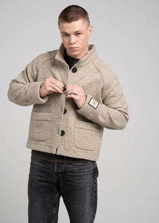 Man wearing a beige jacket with black buttons on a gray background