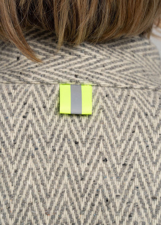 Close-up of a herringbone-patterned fabric with a reflective safety patch.