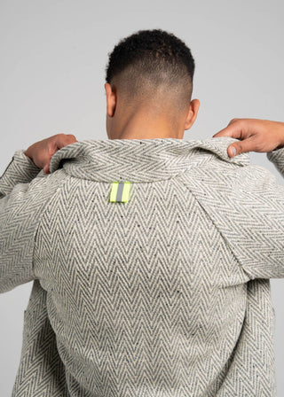 Person wearing a textured gray coat with a visible brand label on a plain background