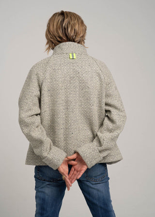 Person wearing a textured beige jacket with a gray background