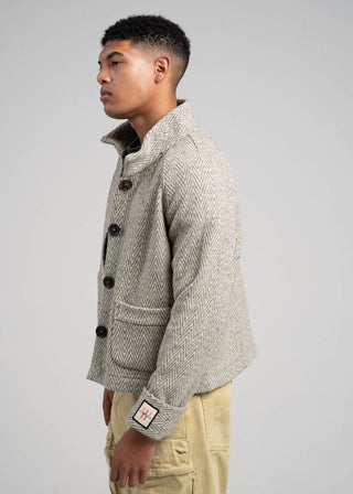 Man wearing a textured gray jacket with black buttons on a plain background