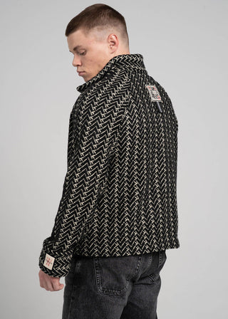 Person wearing a black patterned jacket on a gray background