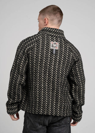 Person wearing a black and white patterned shirt with a visible brand logo on a gray background