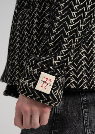Close-up of a black and white patterned garment with a visible brand label on a plain background