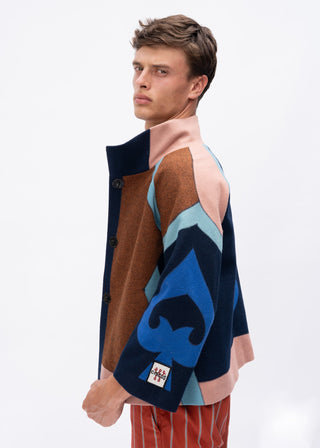 Man wearing a colorful patterned wool jacket with a blue spade design on a white background