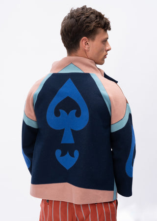 Man wearing a multi-color wool jacket with a blue spade symbol on the back against a white background