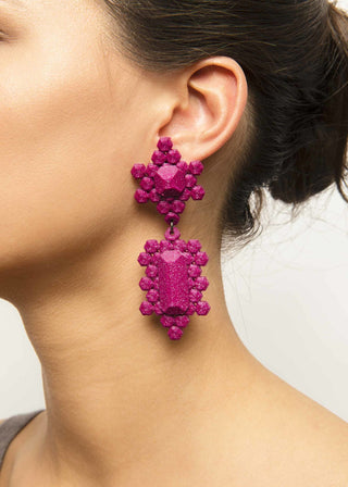 Close-up of a person wearing purple 3D-printed earrings against a neutral background