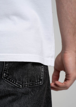 Person wearing a white t-shirt and dark jeans with a plain background