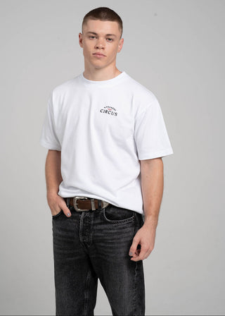 Person wearing a white t-shirt with text and dark jeans on a gray background