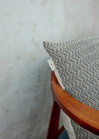 Textured pillow on a wooden chair with a neutral background