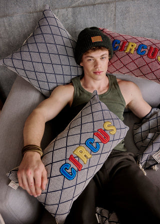 Person lying on a couch with 'Circus' pillows