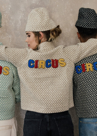 Three people wearing patterned jackets with 'CIRCUS' text on a textured wall background