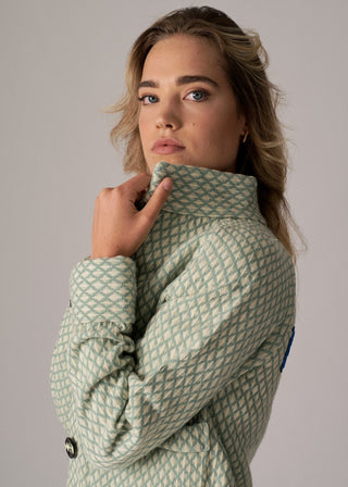 Woman wearing a green quilted jacket against a plain background