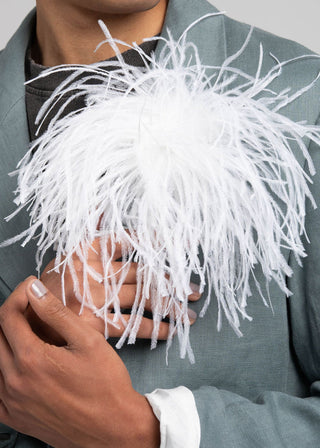 Person wearing a gray suit with a white feathered headpiece